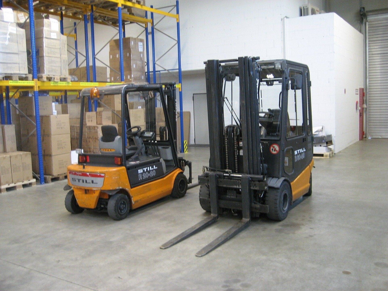 Electric forklifts parked in a warehouse aisle between servicing